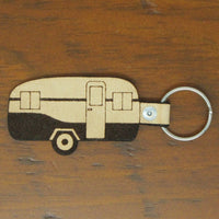 Keychain shaped like a camper on a wooden surface