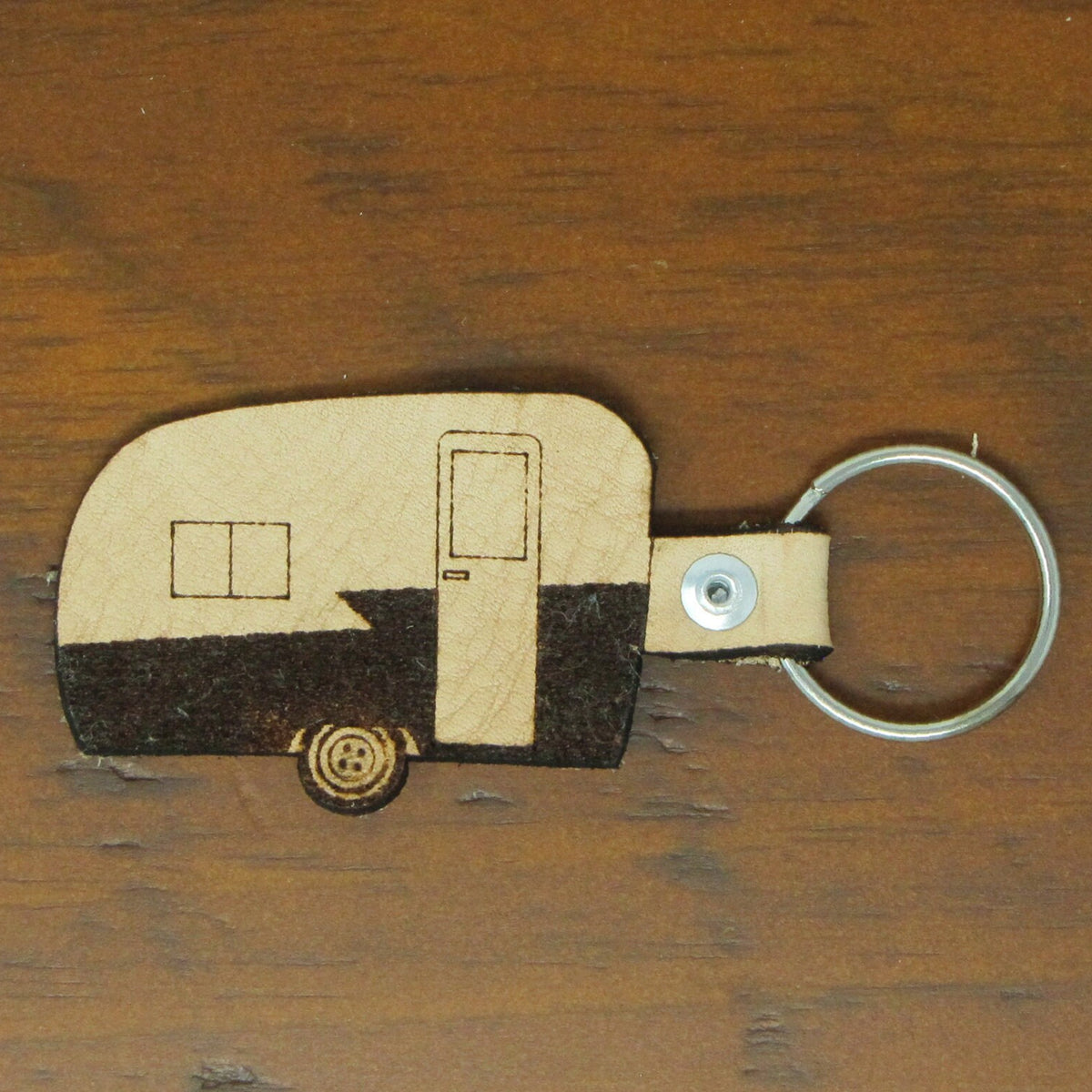 Keychain shaped like a camper on a wooden surface
