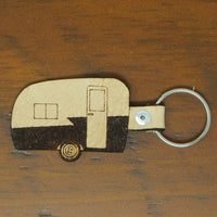 Keychain shaped like a camper on a wooden surface