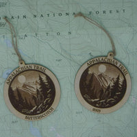 Two Appalachian Trail wooden medallions on a topographic map background