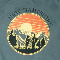 T-shirt with New Hampshire design featuring mountains and people, on a blue background.