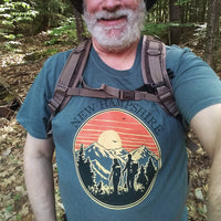 Man in a forest wearing a New Hampshire t-shirt with a backpack.