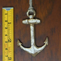 Decorative anchor hanging on a wooden surface with a ruler for scale.
