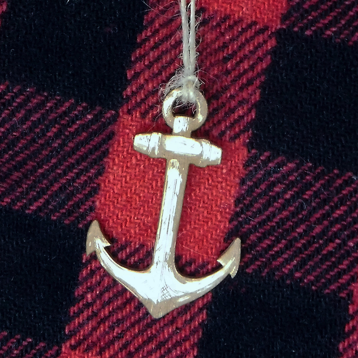 Wood anchor ornament on a red and black plaid fabric background