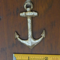 Decorative anchor on a wooden surface with a ruler for scale.