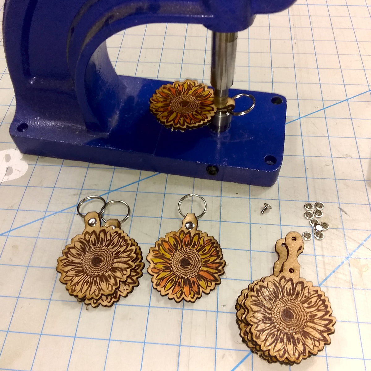 Leather key chains with sunflower designs on a blue vise against a grid background