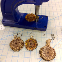 Leather key chains with sunflower designs on a blue vise against a grid background