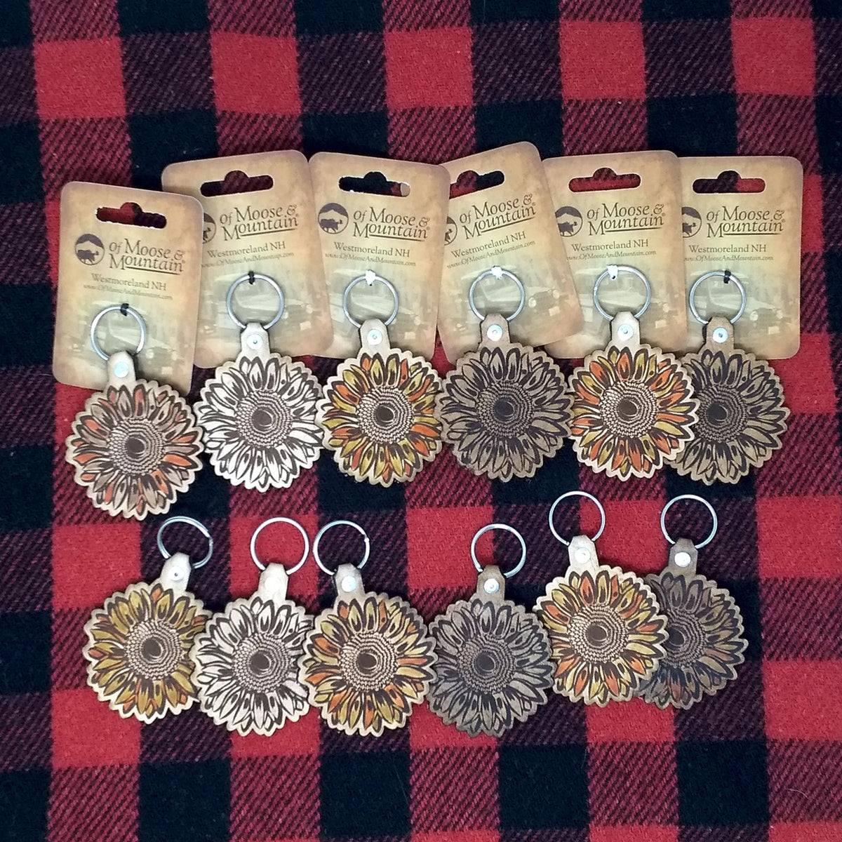 Set of keychains with floral designs on a red and black checkered background