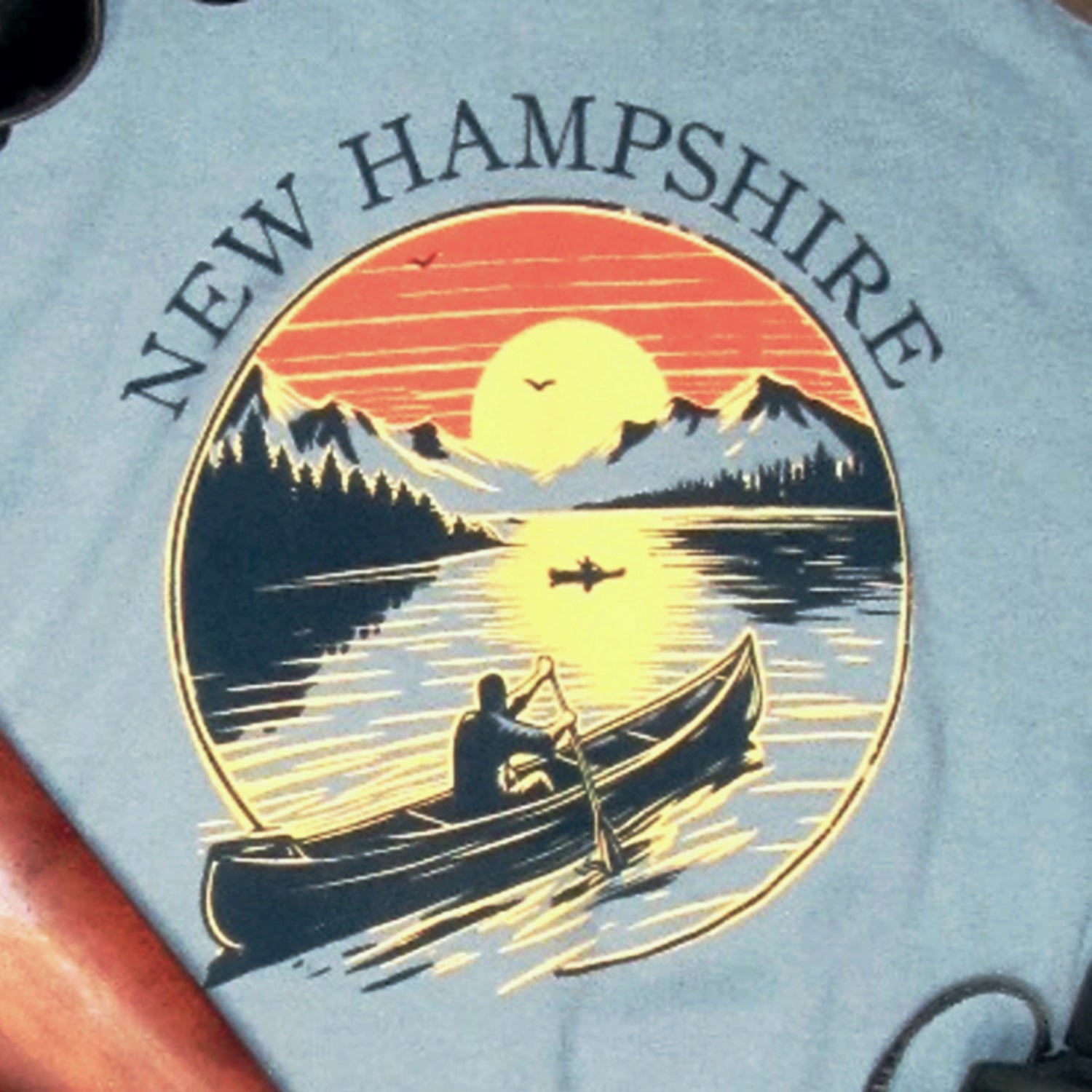 T-shirt with New Hampshire design featuring a sunset over mountains and a canoe.