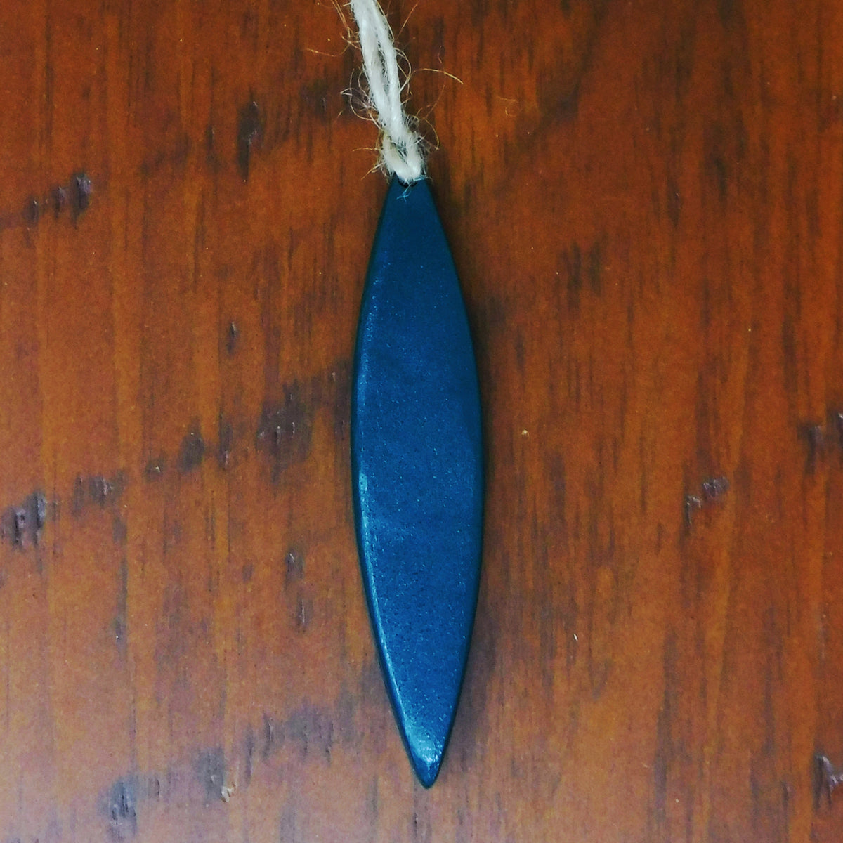 Green canoe-shaped ornament on a wooden surface