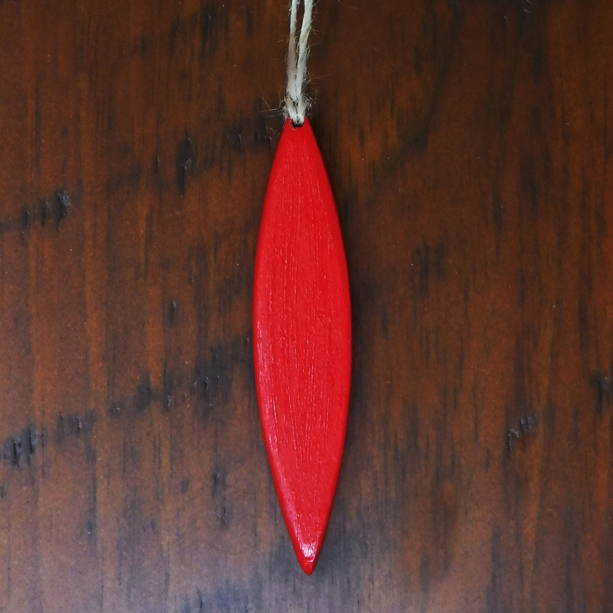 Red wooden canoe ornament hanging on a wooden surface