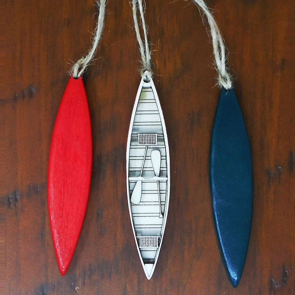 Three decorative canoe-shaped ornaments on a wooden surface