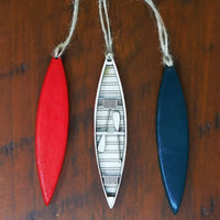 Three decorative canoe-shaped ornaments on a wooden surface