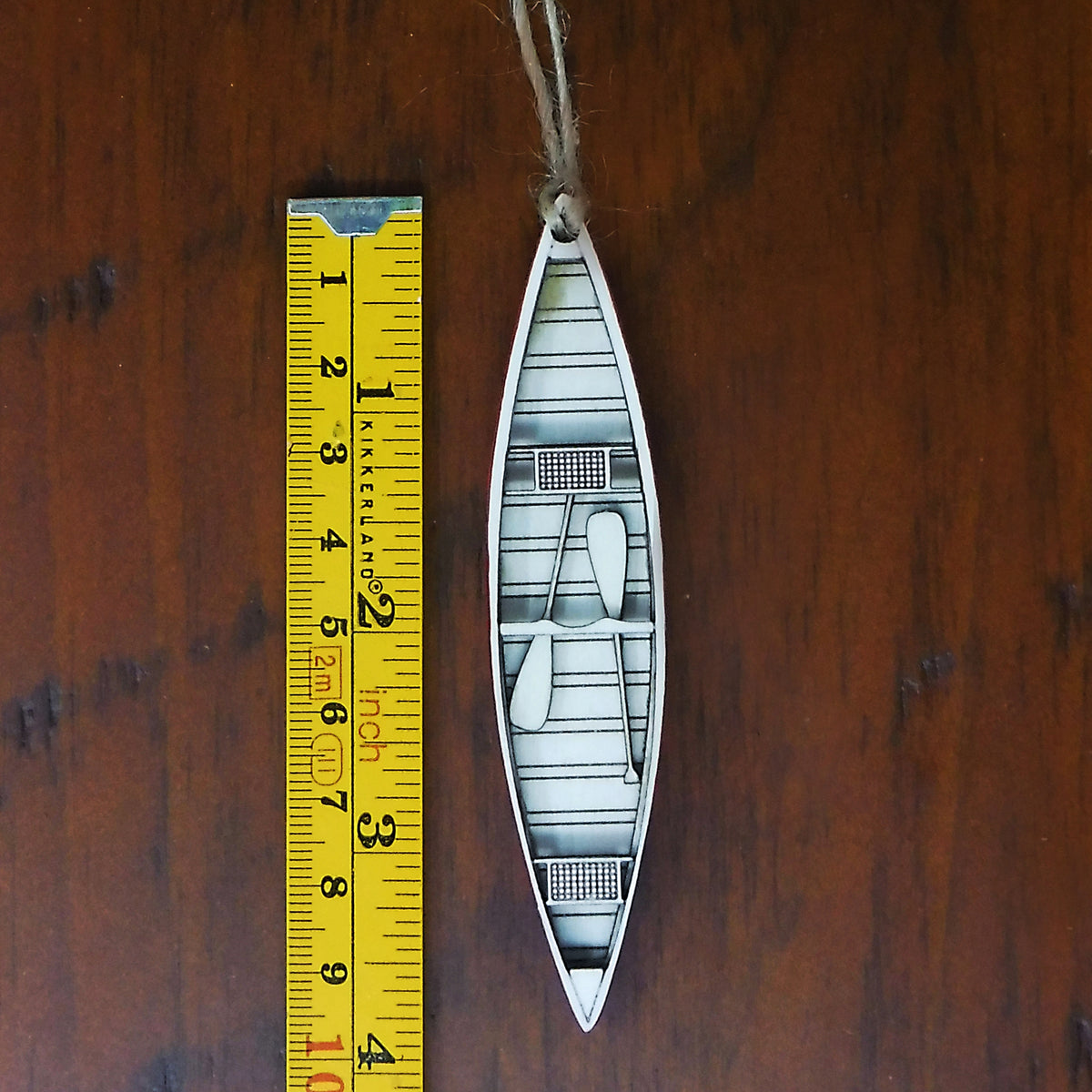 Decorative boat ornament with a ruler for scale on a wooden surface