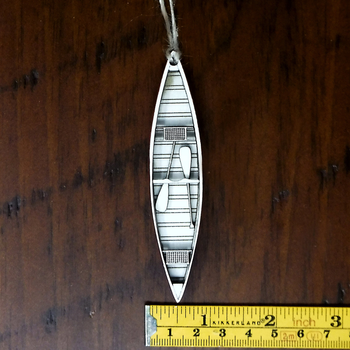 Decorative cutout of a boat design with a ruler for scale on a wooden surface