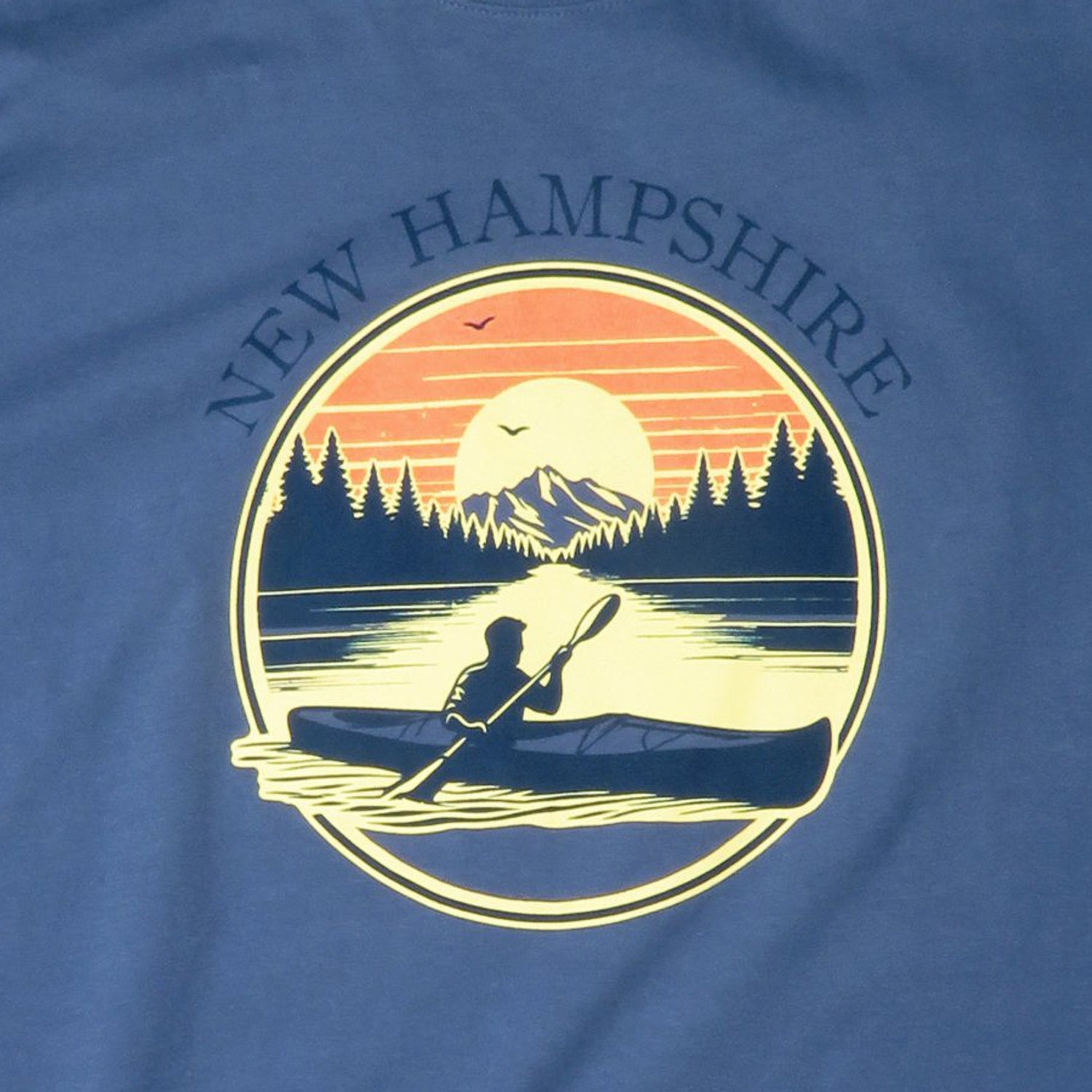 Blue t-shirt with New Hampshire design featuring a kayaker and sunset.