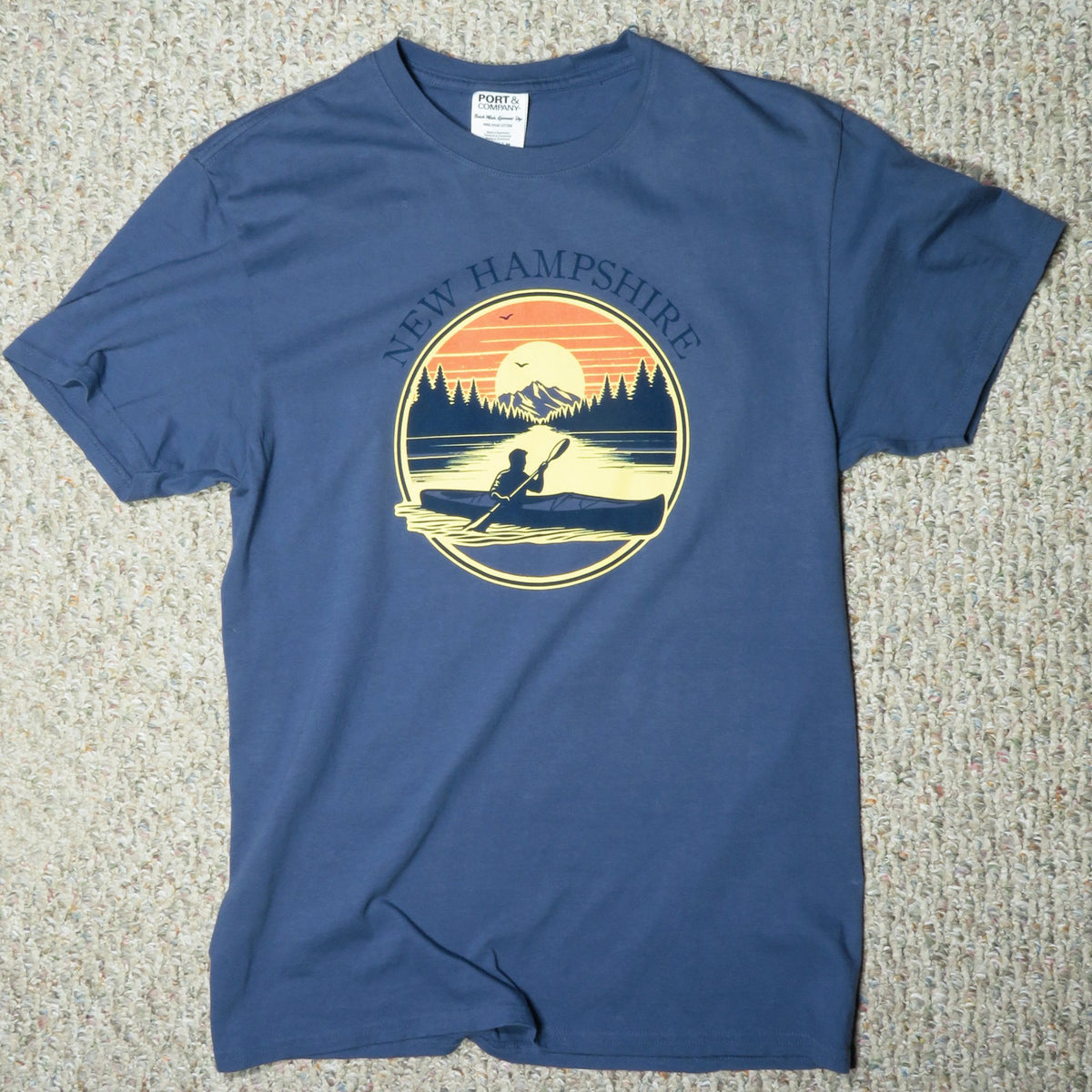 Blue t-shirt with New Hampshire graphic on a textured surface