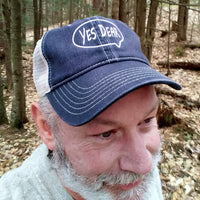 Man wearing a blue cap with 'YES DEAR' text in a forest setting