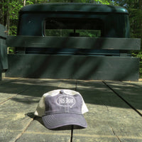 Cap with 'Yes Dear' logo on a wooden surface in front of a green truck.