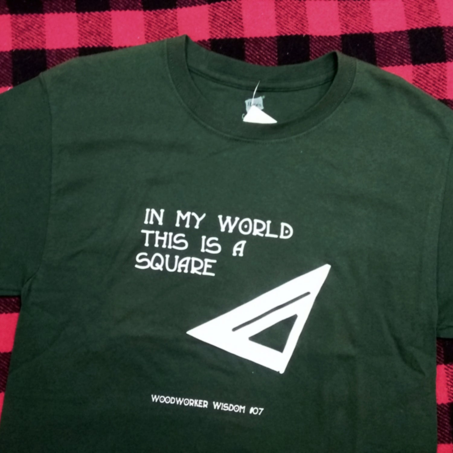 Green t-shirt with white text and logo on a checkered background