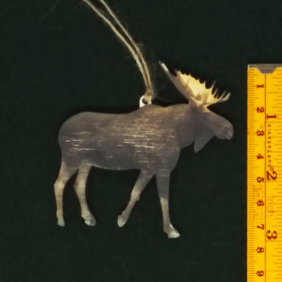 Moose ornament next to a ruler on a black background