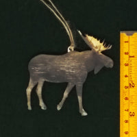 Moose ornament next to a ruler on a black background