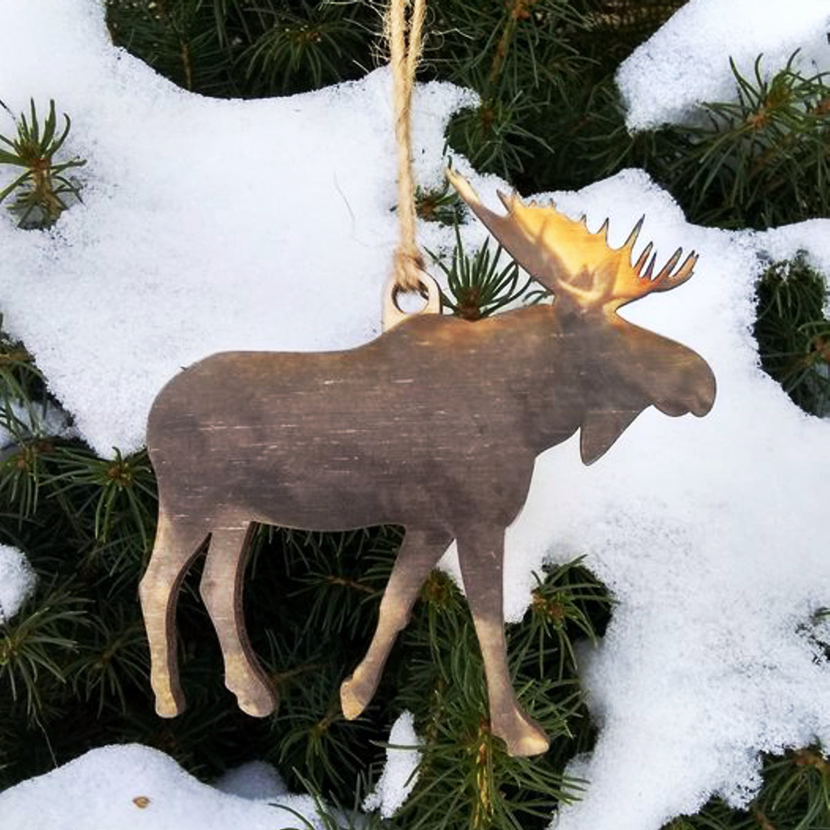 Wooden moose ornament with a light on a snowy branch