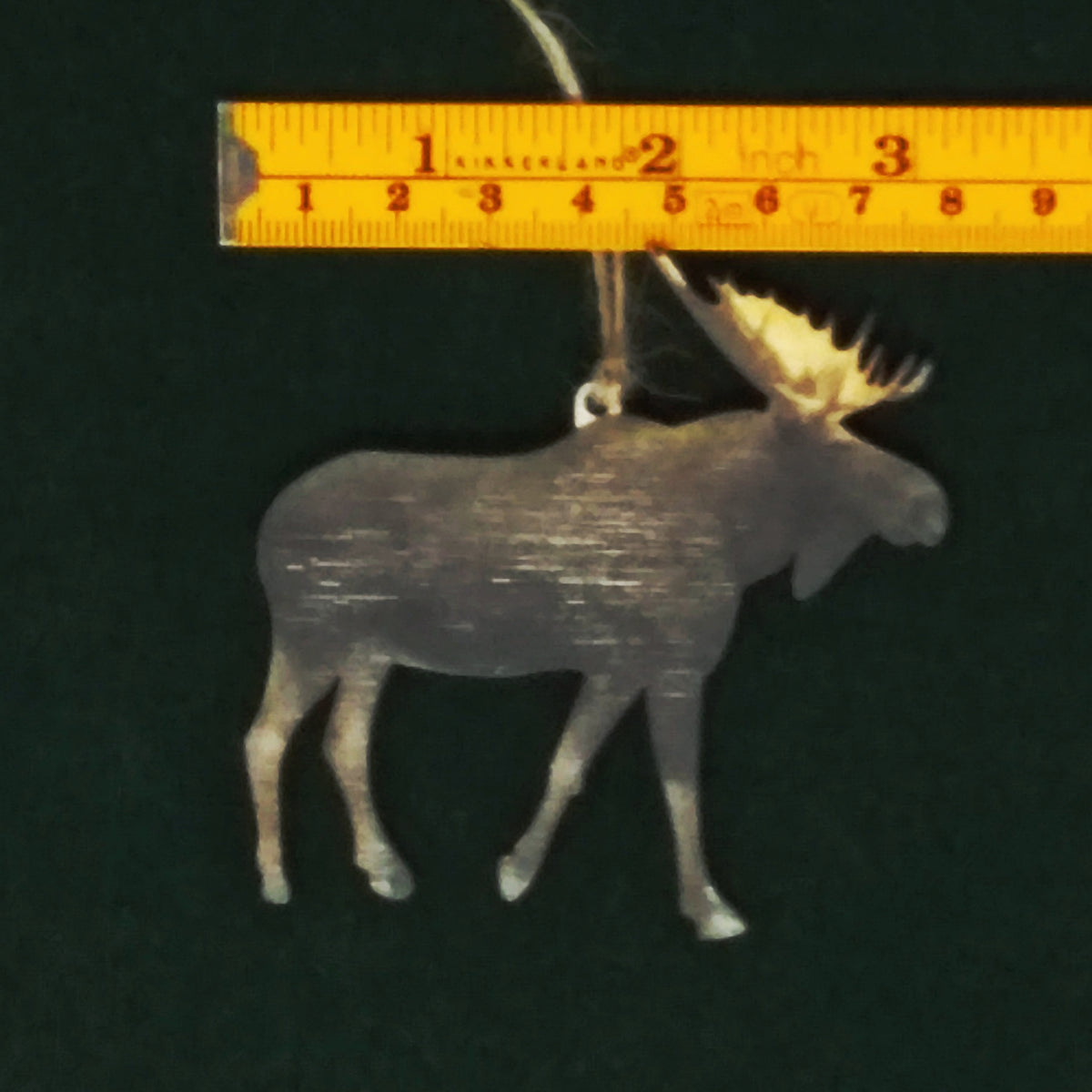Decorative moose ornament with a ruler for scale on a dark background