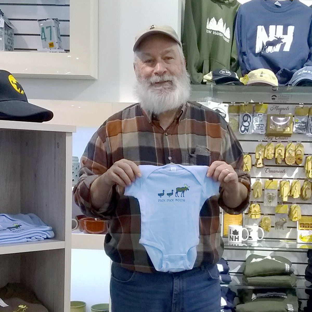 Man holding a baby onesie with a store in the background