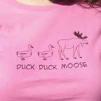 Pink shirt with 'Duck Duck Moose' text and illustrations on a plain background