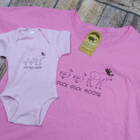 Pink t-shirt and baby onesie with 'Duck Duck Moose' design on a wooden surface