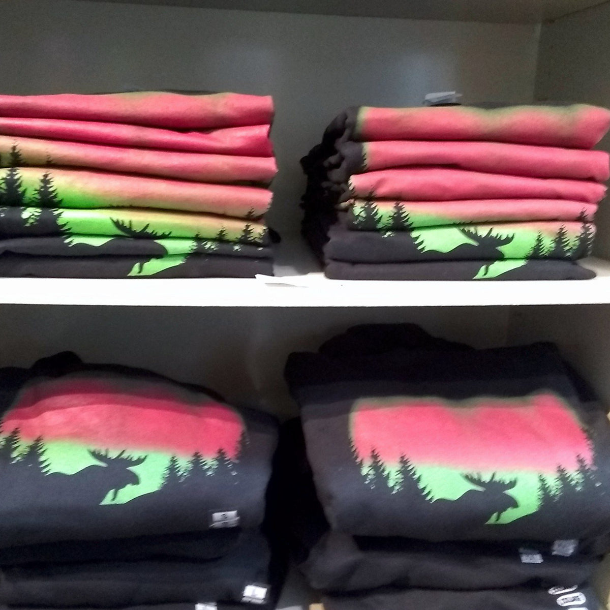 Stacks of folded clothing with nature-themed designs on a shelf.