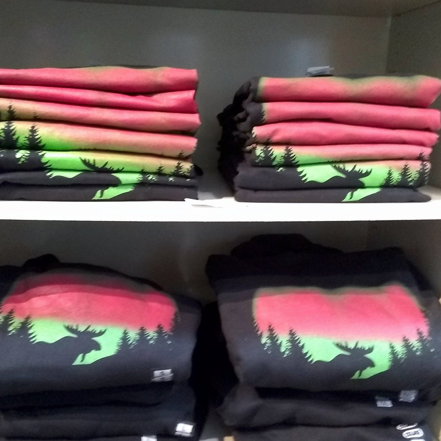 Stacks of folded clothing with nature-themed designs on a shelf.