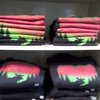 Stacks of folded clothing with nature-themed designs on a shelf.