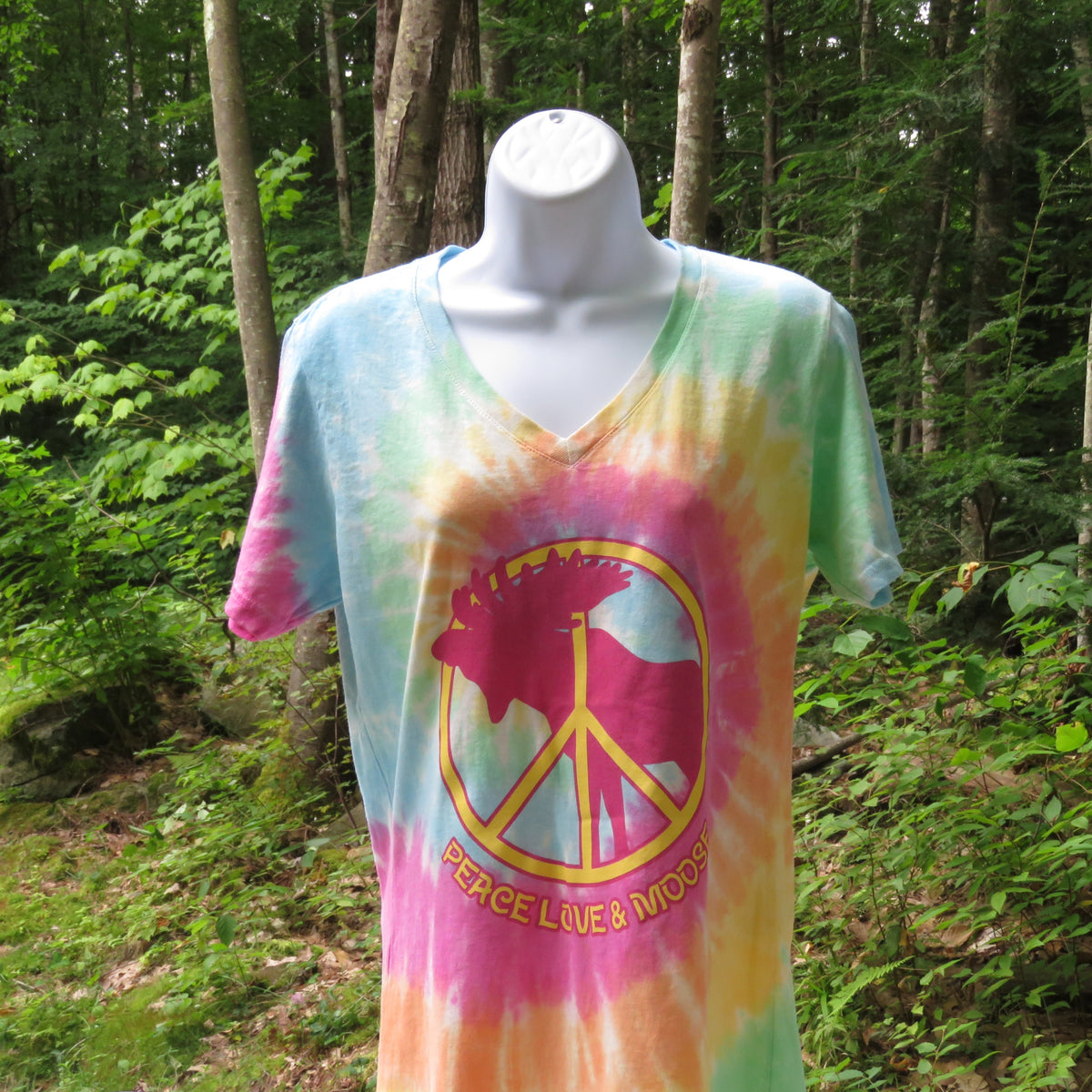 Tie-dye t-shirt with a peace symbol, a moose and "Pease Love & Moose" text on a mannequin in a forest setting.