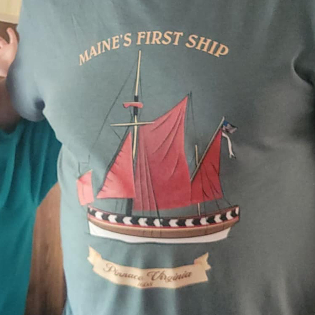 T-shirt with a ship design and text 'MAINE'S FIRST SHIP' on a gray background.