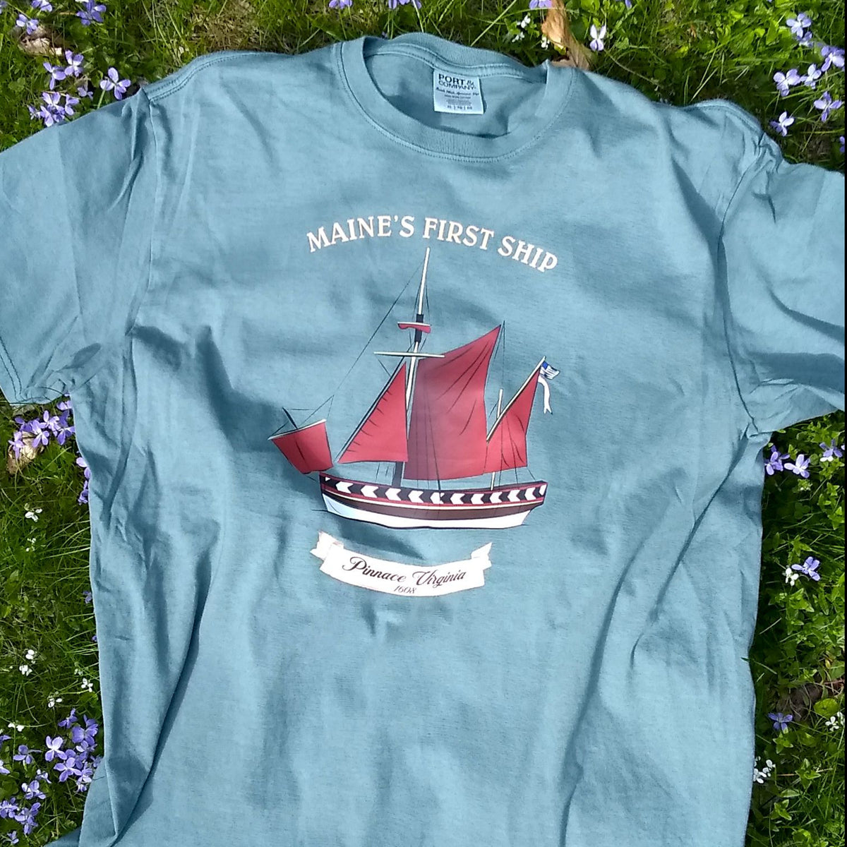 Nordic green t-shirt with a ship graphic and text on grass and flowers