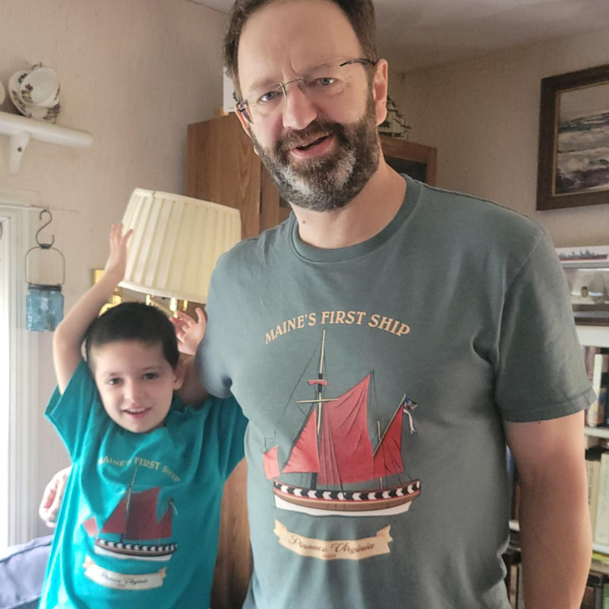 Man and child wearing t-shirts with ship designs in a home setting
