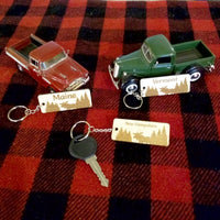 Two toy trucks and keychains on a red and black checkered fabric