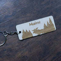 Keychain with 'Maine' and moose design on a wooden surface