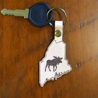 Keychain with a moose design on a wooden surface