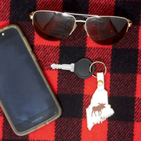 Phone, sunglasses, key with moose keychain on red and black checkered fabric