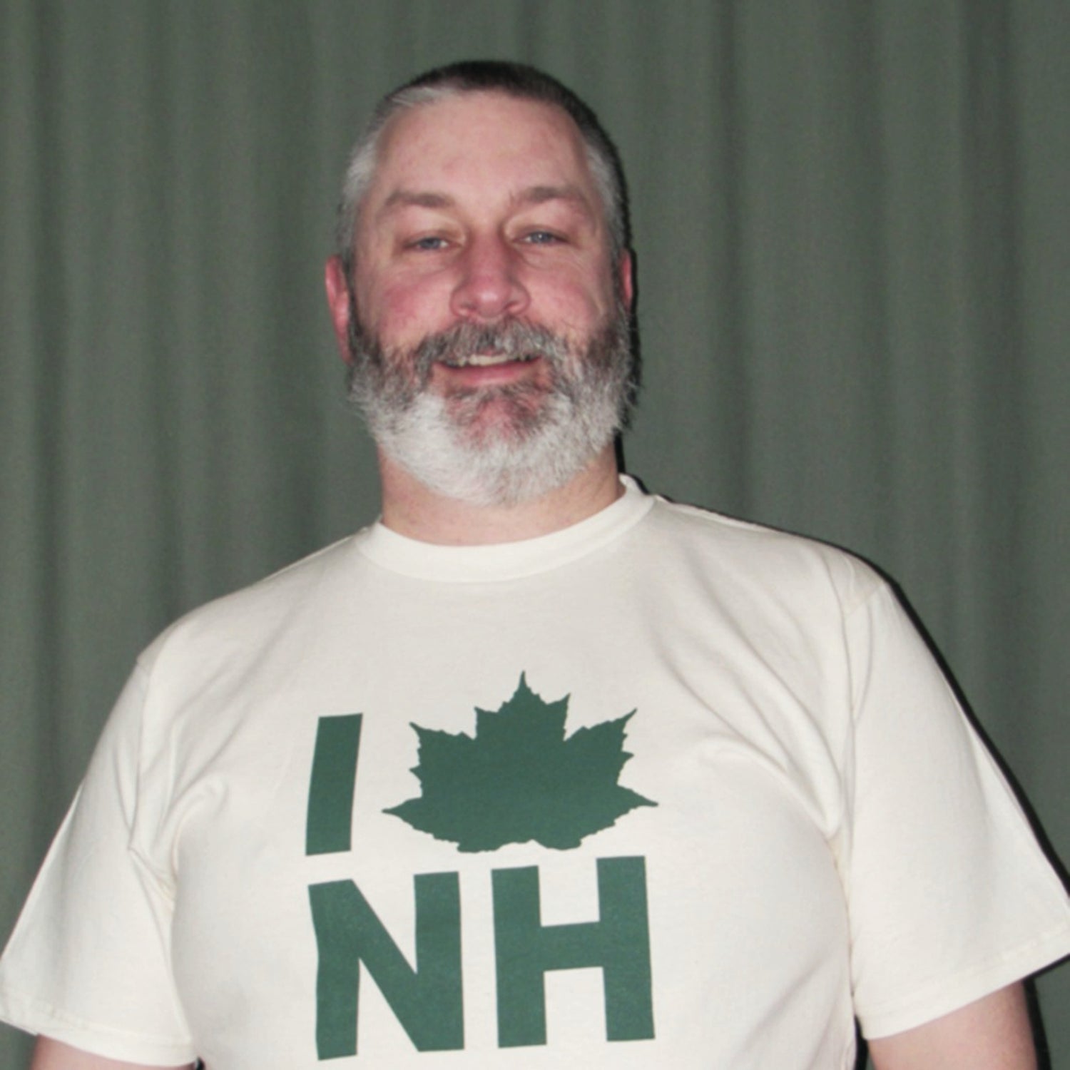 Man wearing a white t-shirt with a green maple leaf and 'I ❤️ NH' text against a plain background
