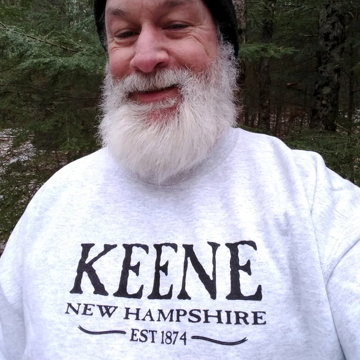 Man wearing a grey t-shirt with 'Keene, New Hampshire Est. 1874' printed on it, standing outdoors.