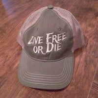 Green cap with 'Live Free or Die' text on a wooden surface