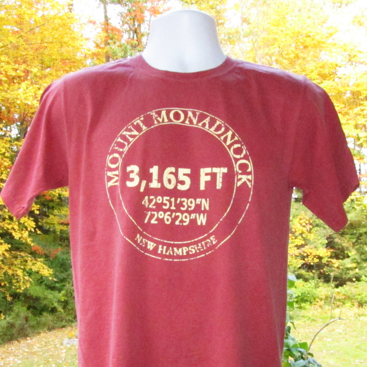 Red t-shirt with Mount Monadnock information on a mannequin against a natural background