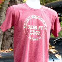 Red t-shirt with white text on a mannequin against a natural background