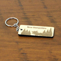 Keychain with 'New Hampshire' and moose design on a wooden surface
