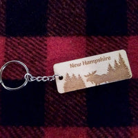 Keychain with 'New Hampshire' and moose design on a red and black checkered fabric background