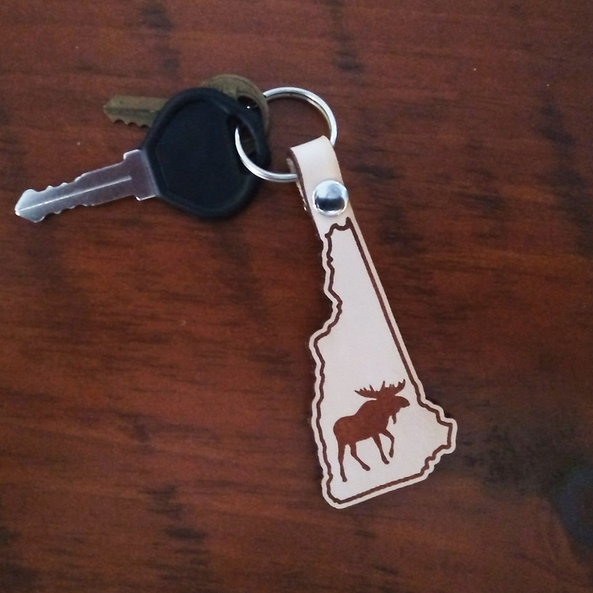 Keychain with a moose design on a wooden surface